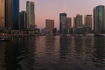 Obraz premium Evening view of the city. Orange sunlight, skyscrapers, buildings, and city streets. On the streets of the Emirates, in a public space.