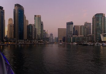Obraz premium Evening view of the city. Orange sunlight, skyscrapers, buildings, and city streets. On the streets of the Emirates, in a public space.