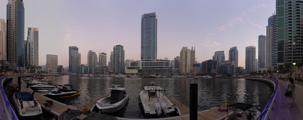 Naklejka premium Evening view of the city. Orange sunlight, skyscrapers, buildings, and city streets. On the streets of the Emirates, in a public space.