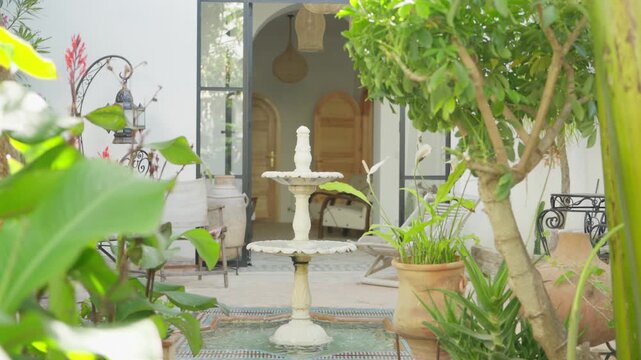 Assilah, Morocco &ndash; May 8, 2024: Zoom-in walk-in shot toward a traditional fountain inside a riad in the old Medina of Assilah, showing courtyard details and Moroccan architectural elements.