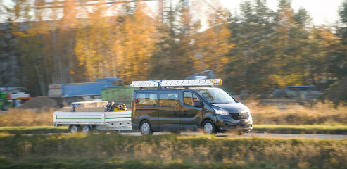 Utility van towing trailer in motion outdoors