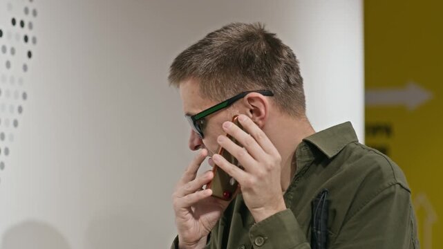 Close up shot of middle-aged Caucasian blind man wearing dark glasses using mobile phone to call his friend or listen to voice messages while standing indoors