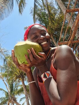 An African woman holding a coconut on the Indian Ocean coast of Mozambique in Vilankulos
