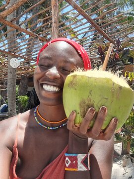 An African woman holding a coconut on the Indian Ocean coast of Mozambique in Vilankulos
