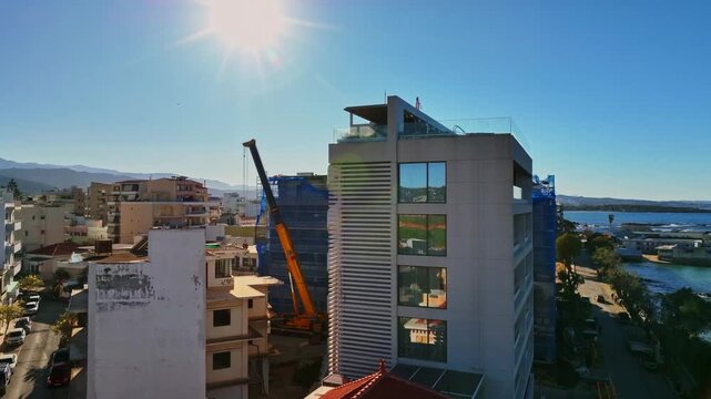 Aerial view of buildings under construction, with a crane amidst the city's architecture under a bright sunny day, Chania, Chania, Greece.