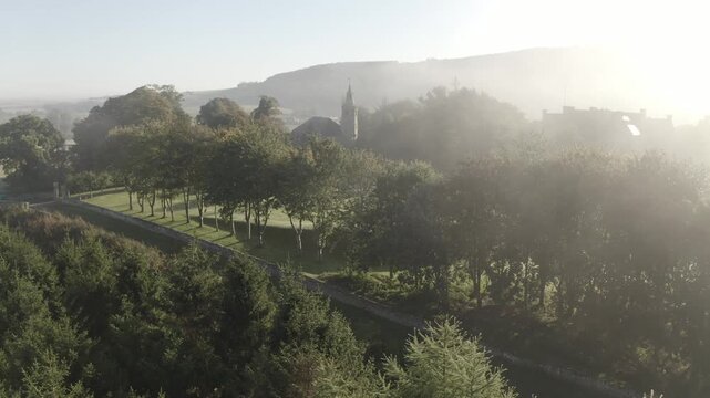 Aerial view of trees, buildings, and fields shrouded in mist, creating a serene and ethereal landscape, Cupar, Scotland, United Kingdom.