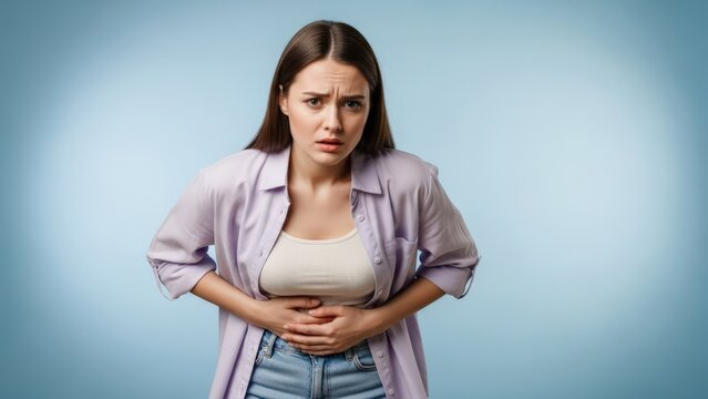 Young woman suffering acute menstrual pain, capturing vulnerability and discomfort against a calming blue background emphasizing health struggles