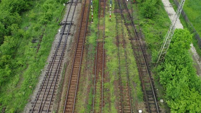 Aerial view of railway tracks cutting through lush greenery, creating a stark contrast between nature and industry, Brasov, Brasov, Romania.