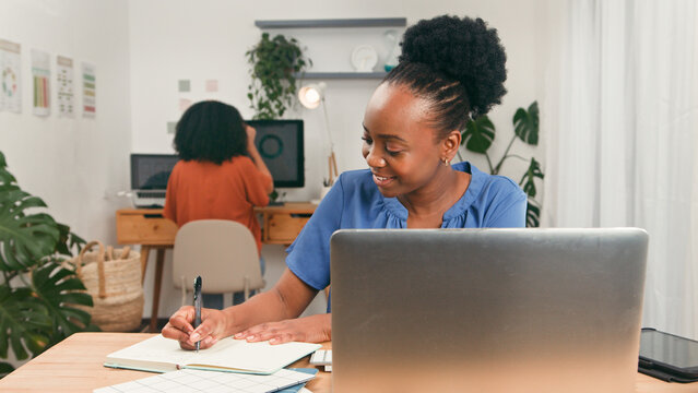 Young Professional Woman Working at Desk with Laptop and Notebook in Modern Office - Powered by Adobe