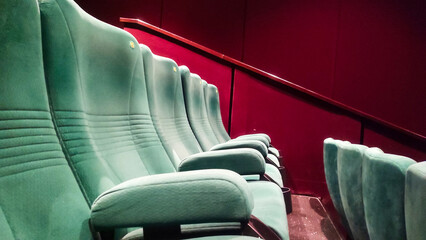 Empty cinema auditorium featuring rows of teal velvet seats facing a blank white screen, ideal for film, entertainment, and cinema concepts.