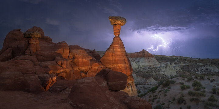 View of striking lightning electrifies the sky behind the sandstone formations and arid landscape, painting a dramatic scene of nature's power, Escalante, Utah, United States.