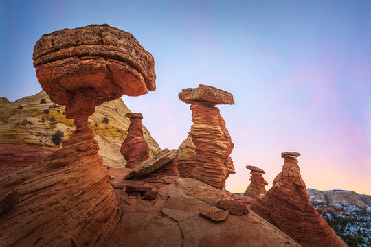 View of whimsical sandstone hoodoos rise majestically against a soft gradient sky, showcasing the raw beauty of the desert landscape, Escalante, Utah, United States.