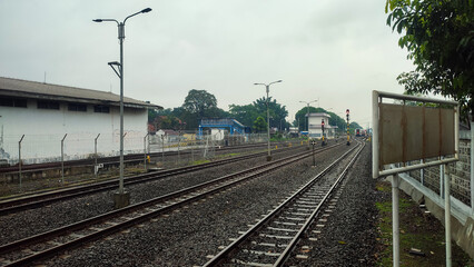 Obraz premium Parallel railway tracks with steel rails, concrete sleepers, red fasteners, and grey stone ballast, featuring a small trackside marker, transportation, infrastructure, and rail industry concepts.