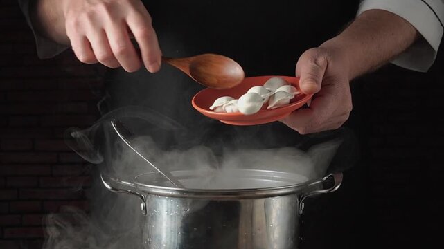 Chef prepares dumplings by placing them into a steaming pot, showcasing the cooking process in a kitchen with visible steam and utensils