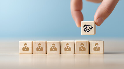 Hand putting hand shaking which print screen on wooden cube block in front of human icon for Business Partnership and Agreement Concept