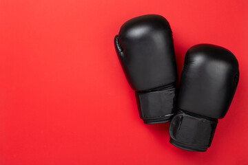 Black boxing gloves on color background, top view