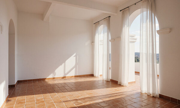Mediterranean Sunroom - Empty sunroom with arched windows, smooth white walls, terracotta tiles glowing in sunlight, sheer curtains partially drawn