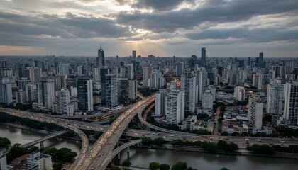Obraz premium Aerial view of a bustling modern city with dense skyscrapers, elevated highways, and urban sprawl under a dramatic cloudy sky, capturing the essence of South American metropolis like São Paulo in dyna