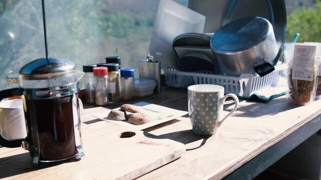 A cozy outdoor setup with a french press, coffee mug, and various kitchen items on a wooden surface. Perfect for a relaxing moment in Cederberg, South Africa