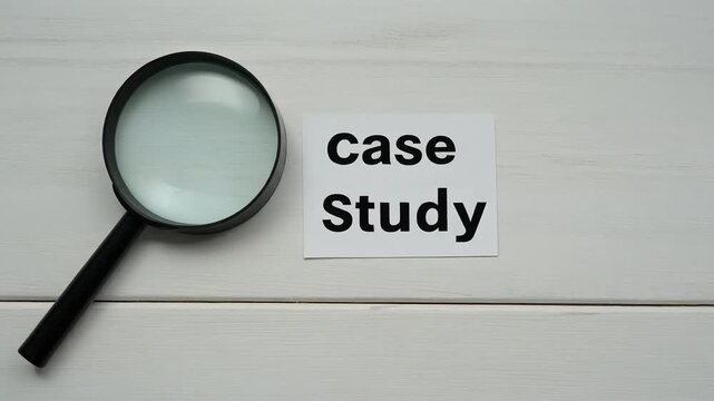 A magnifying glass beside a paper labeled "case Study" on white wooden planks, symbolizing detailed examination and analysis in academic, business, or research contexts.
