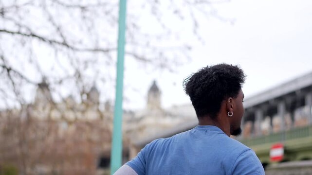 Young athletic man running along a tree lined path next to a river and then jogging up a stone staircase in paris, demonstrating endurance and determination during his outdoor urban workout