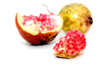 Studio shot of vibrant red pomegranate arils in sharp focus, with a halved and whole pomegranate softly blurred in the background. Clean white background highlights freshness, and juicy texture