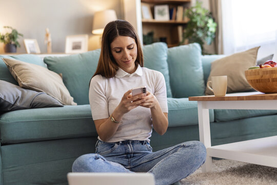 Woman, laptop and phone with remote work from home, web chat or thinking for web design job on floor. Freelance entrepreneur, computer and developer for contact, problem solving and typing in house.