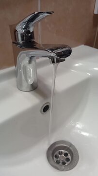 The water is flowing from the faucet. Vertical Video