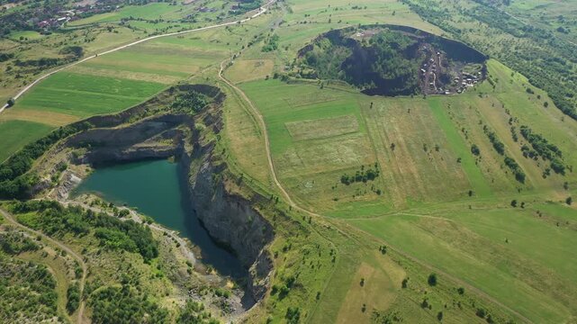 Aerial view of the dramatic landscape, a quarry with turquoise water contrasts with the green fields, Racos Volcano, Racos, Judetul Brasov, Romania.