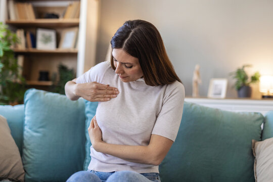 Adult woman doing breast self-examination at home. Young Caucasian woman palpating her breast by herself that she concern about breast cancer. Healthcare and breast cancer concept.