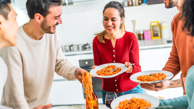 Happy group of friends eating pasta at home dinner party - Cheerful young people having lunch break together - Life style concept with guys and girls celebrating thanksgiving - Bright filter