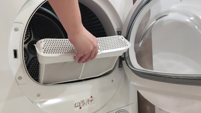 Woman is cleaning filter of drying machine 