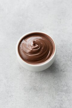 Chocolate hazelnut spread Chocolate hazelnut spread in a white sauce bowl on a grey background. View from an angle