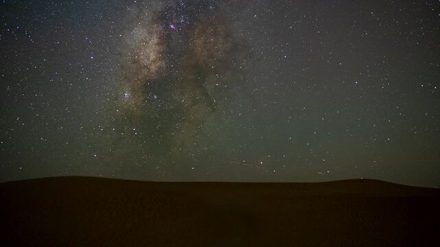 Stunning timelapse of the night sky transition of moonset and Milky Way galaxy motion in the desert sand dune in a remote location