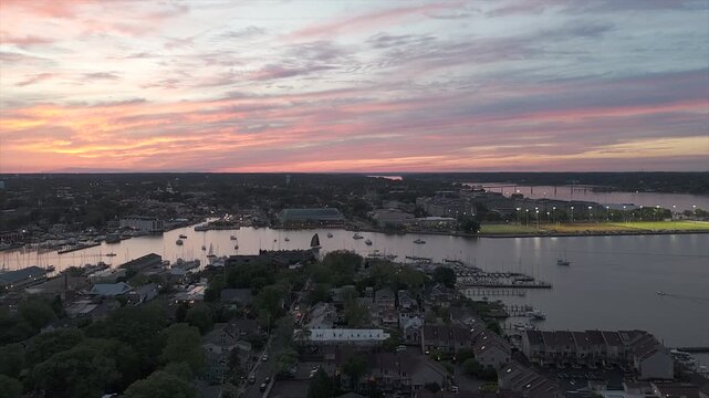 A Warm Sunset Spreads Across the Sky as the Marina and Quiet Waterways Below Grow Calm - Aerial Pullback Shot over the Naval Academy in Annapolis, MD.