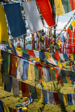 View of vibrant prayer flags strung across the landscape, creating a colorful tapestry against the green hills, Kiki La Pass, Bumthang, Bhutan.