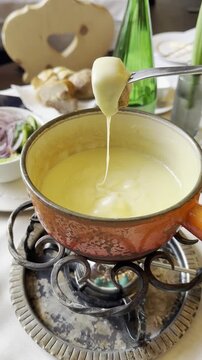 raditional Swiss cheese fondue in rustic pot with melted cheese and bread on cozy restaurant table. Alpine cuisine, gourmet food, winter comfort meal, close-up, warm atmosphere, European dining.
