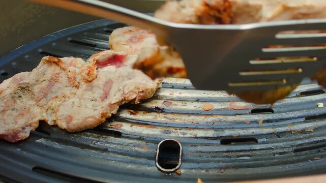Cook flips the meat on the grill with spatula