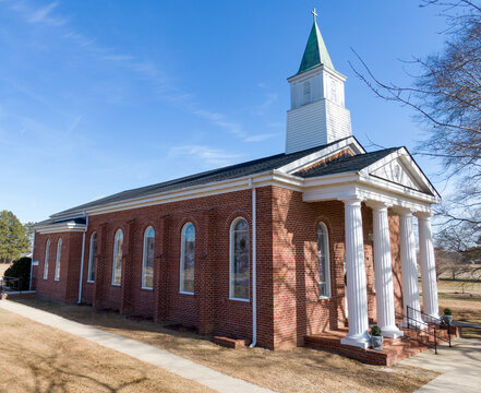 Classic Southern Baptist Red Brick Church with White Columns and Weathered Copper Steeple With Green Patina