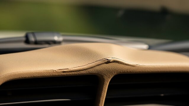 Damaged leather car dashboard interior close-up.