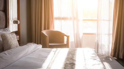 Fototapeta premium A serene hotel bedroom bathed in morning sunlight, featuring a neatly made bed and sheer curtains.