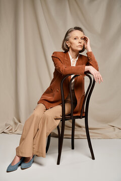 Elegant mature woman seated gracefully, showcasing timeless beauty and poise in soft lighting