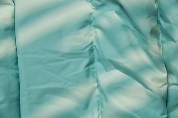 Close-up view of a light blue fabric with folds and textures in natural light during the day