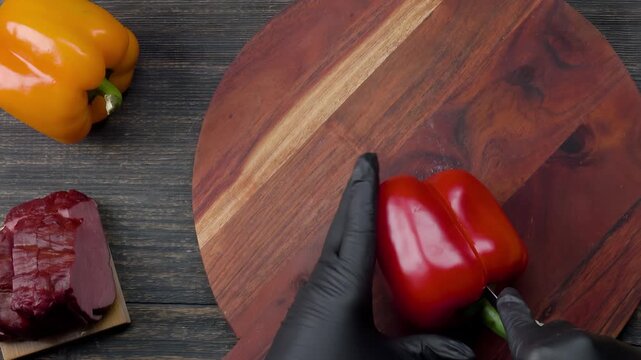 knife slicing red bell pepper on wooden board. Fresh vegetable ingredient preparation for filo pastry pie. Kitchen cooking process
