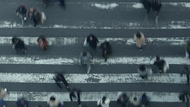 Abstract motion blur of pedestrians crossing a city road from above.