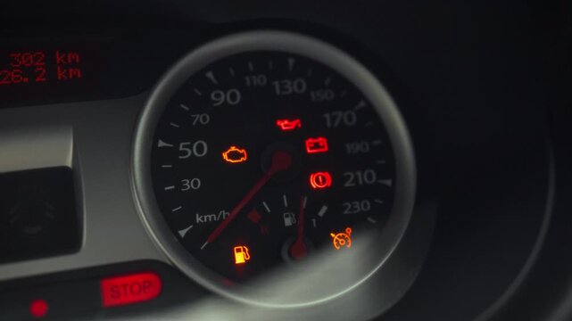 The driver turns car key in the ignition switch, initiating engine startup, as dashboard warning lights flicker momentarily, signaling the start sequence has begun, preparing the vehicle for operation