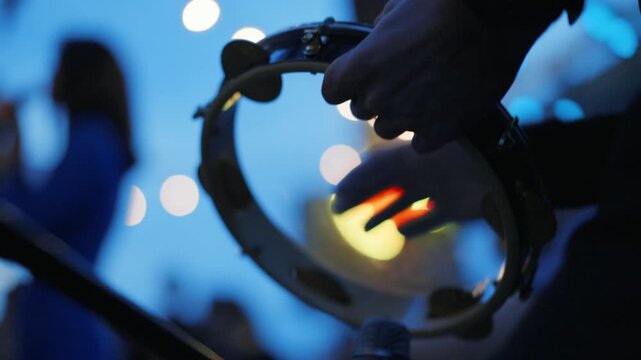 Musician playing tambourine creating rhythm at concert event