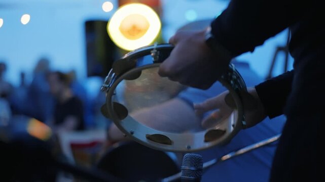 Musician playing tambourine creating rhythm at concert event