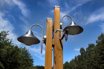 Wooden post with twin metal lamps against a bright blue sky