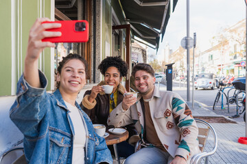 Obraz premium Diverse friends taking selfie enjoying coffee at outdoor cafe